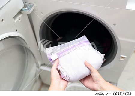洗濯ネットに入れておしゃれ着洗いをする主婦の手元 83187803