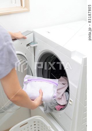 洗濯ネットに入れておしゃれ着洗いをする主婦の手元 83187805
