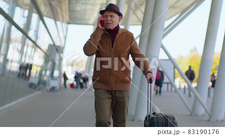 Senior tourist grandfather man walking on international airport hall, using mobile phone, talking Senior tourist grandfather man walking on international airport hall, using mobile phone, talking 83190176