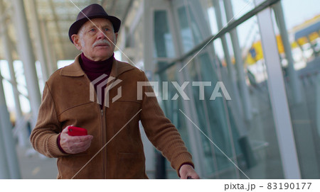 Senior tourist grandfather man walking on international airport hall, using mobile phone, texting Senior tourist grandfather man walking on international airport hall, using mobile phone, texting 83190177