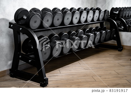 Rows of metal dumbbells on rack for bodybuilding in gym 83191917
