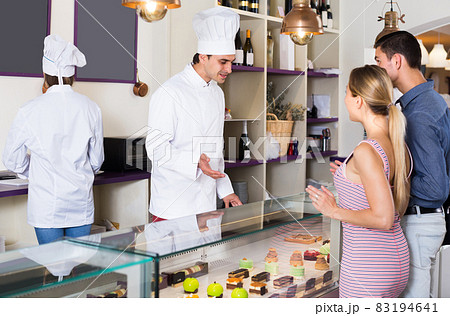 Cheerful pastry man is serving visitors 83194641