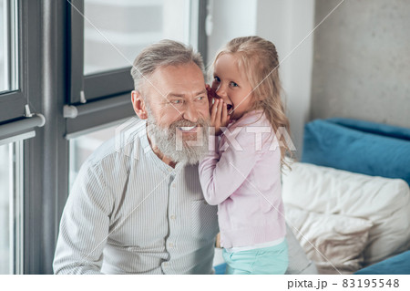 A cute blonde girl sharing secrets with her father A cute blonde girl sharing secrets with her father 83195548
