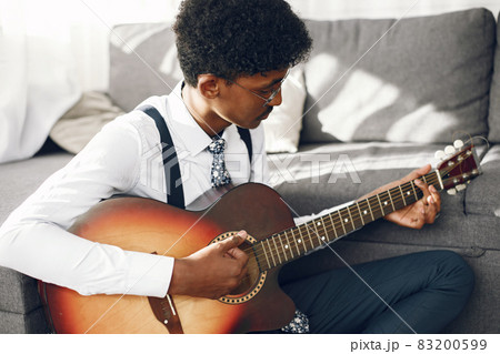 Indian man playing the guitar in a living room 83200599