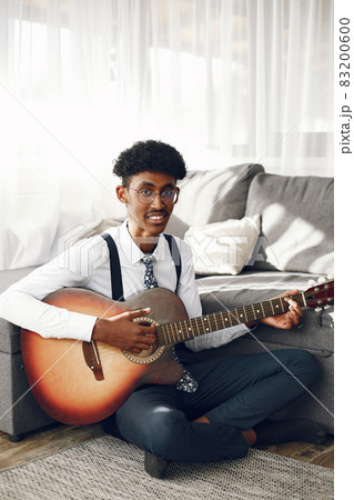 Indian man playing the guitar in a living room 83200600