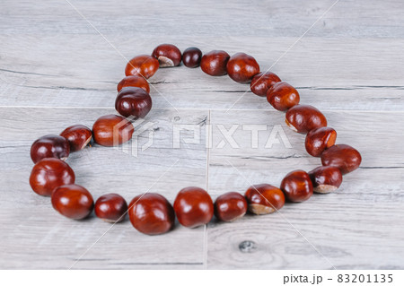 Chestnuts in a heart shape on a wooden background Chestnuts in a heart shape on a wooden background 83201135