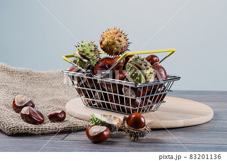 Chestnuts in a metal grocery basket on a wooden background 83201136