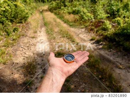 Compass in hand at road in the forest. Compass in hand at road in the forest. 83201890