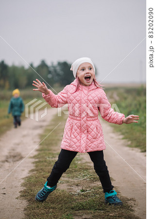 Little caucasian girl running in the field with her brother making funny faces 83202090