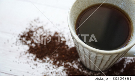 木製の床に散らばるグラインドされたコーヒー豆とコーヒカップ 木製の床に散らばるグラインドされたコーヒー豆とコーヒカップ 83204361
