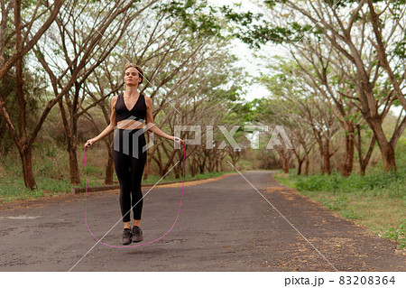 Woman in black sportwear jumping rope Woman in black sportwear jumping rope 83208364