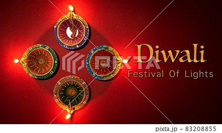 Happy Diwali - Clay Diya lamps lit during Dipavali, Hindu festival of lights celebration. Colorful traditional oil lamp diya on red .background Happy Diwali - Clay Diya lamps lit during Dipavali, Hindu festival of lights celebration. Colorful traditional oil lamp diya on red .background 83208855