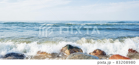 Waves of the blue sea crashing against the coastal rocks, horizon line in the sea 83208980