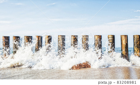 Waves crashing on a wooden breakwater against the background of the sea, the sea horizon and the sky 83208981