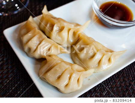 Japanese dish - dumplings gyoza with soy sauce on white plate Japanese dish - dumplings gyoza with soy sauce on white plate 83209414
