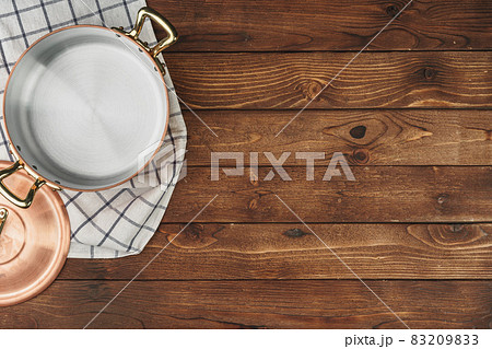 New copper cooking pot on wooden table, view from above New copper cooking pot on wooden table, view from above 83209833