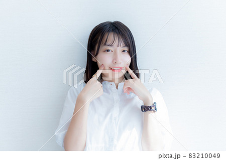 指を頬に当てる笑顔の女性 83210049