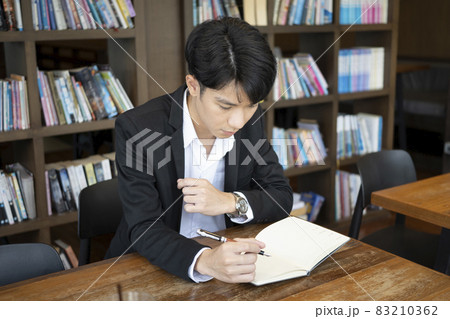 Young businessman in suit holding pen and writing information on notebook. Young businessman in suit holding pen and writing information on notebook. 83210362