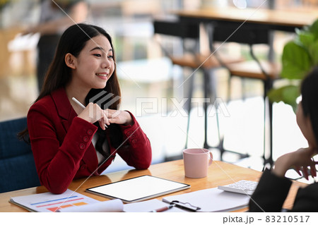 Cheerful businesswoman working with her colleague in modern office. 83210517