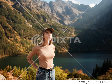Wanderlust and travel concept. Stylish traveler girl in cap looking in front of mountain Wanderlust and travel concept. Stylish traveler girl in cap looking in front of mountain 83211352