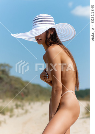 Topless woman covering breast on beach 83211849