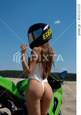 Seductive woman in swimsuit near motorbike on beach Seductive woman in swimsuit near motorbike on beach 83212125