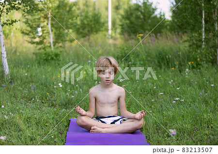 preschooler boy meditating outdoors on nature in summer time preschooler boy meditating outdoors on nature in summer time 83213507