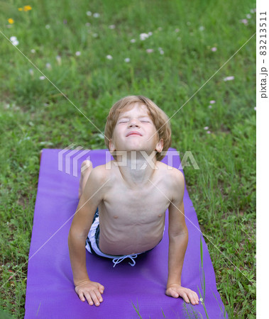 Little caucasian boy doing yoga cobra position outside in outdoor. Kids Yoga Little caucasian boy doing yoga cobra position outside in outdoor. Kids Yoga 83213511