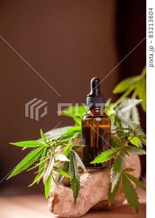 bottle of serum with branch of cannabis on natural stone on background of craft paper. 83213604