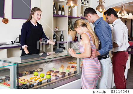 Hospitable female confectioner serving visitors 83214543