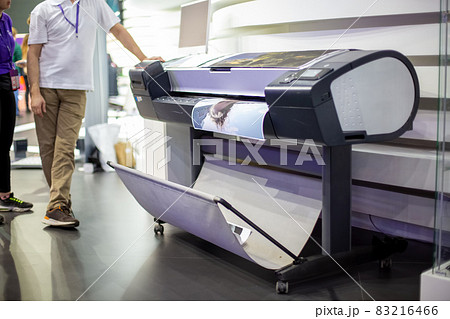 plotter prints a poster. standing next to people in blur. close-up, background in blur 83216466