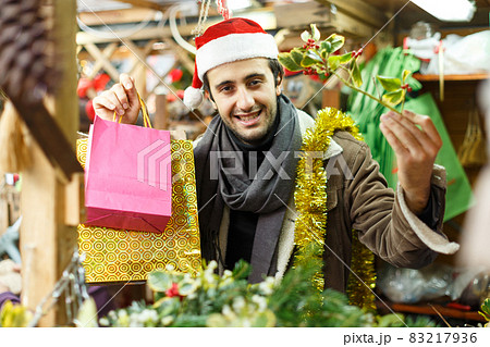 Happy young man Christmas hat with looking toys at fair outdoor 83217936