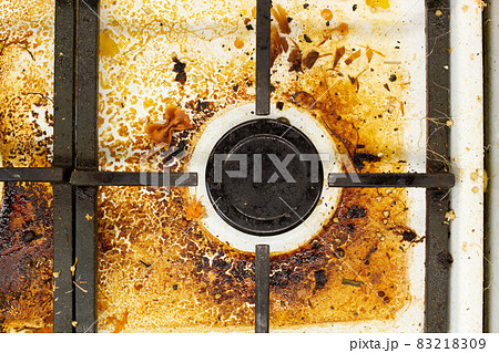 Dirty gas stove surface. Medium gas burner and cast iron grate of a gas oven surrounded by old leftovers of food and drinks. Top area surface and burner heads needs cleaning from burnt-on grease Dirty gas stove surface. Medium gas burner and cast iron grate of a gas oven surrounded by old leftovers of food and drinks. Top area surface and burner heads needs cleaning from burnt-on grease 83218309