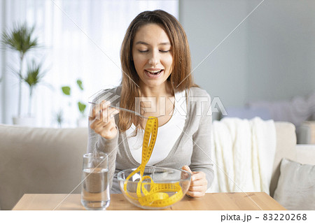 Young woman holding fork with measuring tapes. 83220268