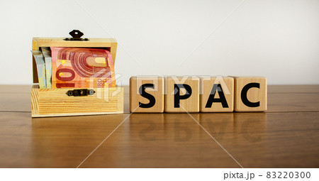 SPAC, special purpose acquisition company symbol. Wooden cubes with word 'SPAC' on beautiful white background, copy space. Euro bills. Business and SPAC, special purpose acquisition company concept. 83220300