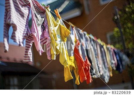 Baby cute clothes hanging on the clothesline outdoor. Child laundry hanging on line in garden on green background. Baby accessories. 83220639