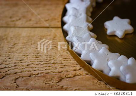 A white hexagonal star-shaped cookie stands in a metal plate on a wooden board 83220811
