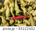 One red ripe chili among plenty of green bell pepper chilies.  83222402