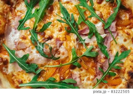 Close-up of pizza with bacon in a disposable dish. Top view of takeaway food in a fast food cafe. On photo - mozzarella cheese, tomatoes, and red basil. The classic recipe. Food for family and 83222505