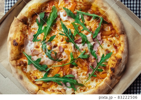 Close-up of pizza with bacon in a disposable dish. Top view of takeaway food in a fast food cafe. On photo - mozzarella cheese, tomatoes, and red basil. The classic recipe. Food for family and Close-up of pizza with bacon in a disposable dish. Top view of takeaway food in a fast food cafe. On photo - mozzarella cheese, tomatoes, and red basil. The classic recipe. Food for family and 83222506