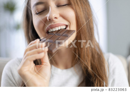 Woman biting a chocolate bar Woman biting a chocolate bar 83223063