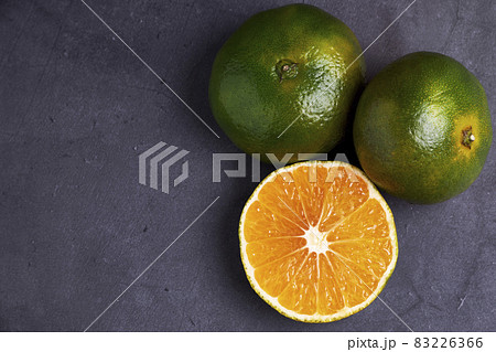 Fresh and juicy green mandarins on a dark background. Vegetarian food concept Fresh and juicy green mandarins on a dark background. Vegetarian food concept 83226366