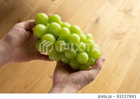 シャインマスカットの房を持つ女性　ぶどう　（9月） 83227891