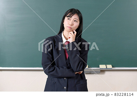 黒板の前で悩む制服を着た笑顔の女子学生 黒板の前で悩む制服を着た笑顔の女子学生 83228114