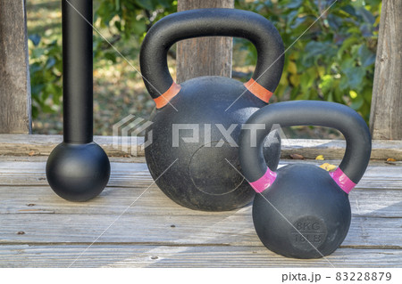 steel mace (or macebell) and kettlebells on a wooden deck 83228879
