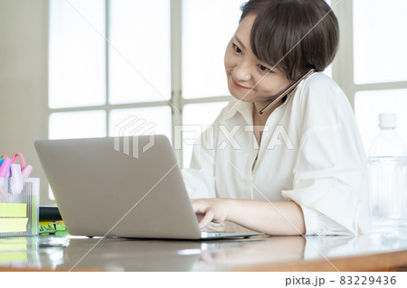在宅勤務で、電話応対しながら入力する、若い女性 在宅勤務で、電話応対しながら入力する、若い女性 83229436