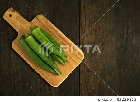 木目のテーブルにあるまな板の上に置かれた複数のオクラ 83229853