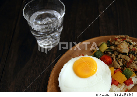 木目のテーブルの上におかれたタイ料理のガパオライスと水 木目のテーブルの上におかれたタイ料理のガパオライスと水 83229864