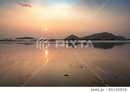 太平洋日向灘に昇る日出で黄昏色に染まった日南海岸の大堂津海水浴場浜と沖に浮かぶ七つ岩と木場島とビロ岩 83230859