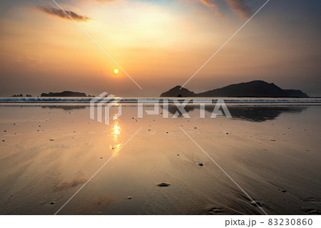 太平洋日向灘に昇る日出で黄昏色に染まった日南海岸の大堂津海水浴場浜と沖に浮かぶ七つ岩と木場島とビロ岩 83230860